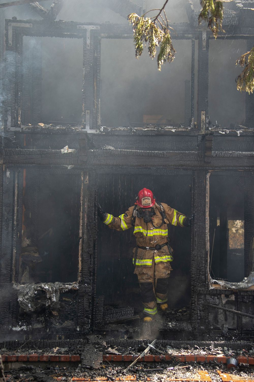 Firefighter emerges from charred remains of burned building during emergency response.