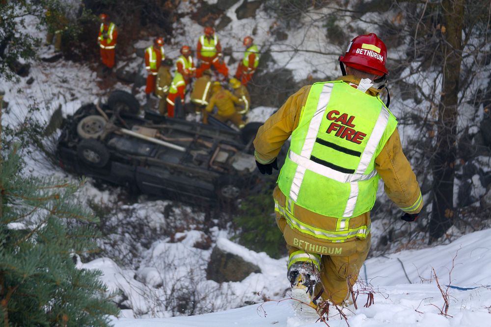 Emergency responders assess overturned vehicle in snowy conditions.
