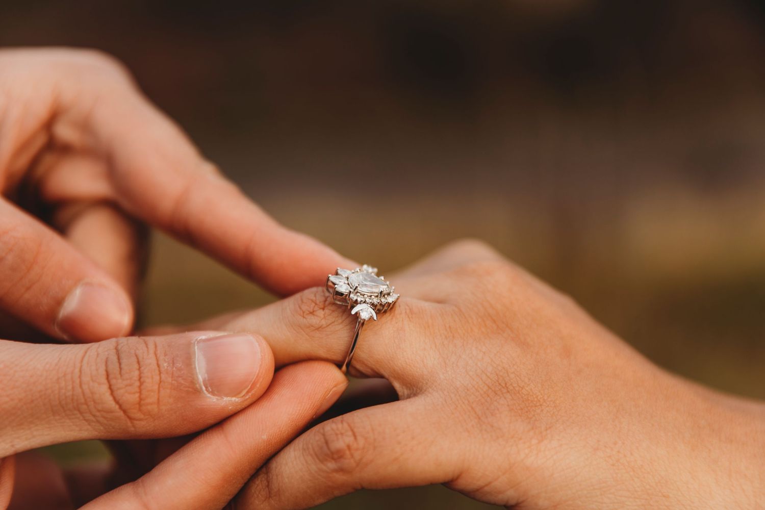 A close-up shot of hands placing a diamond engagement ring on a finger during a proposal moment. Proposal in Edinburgh