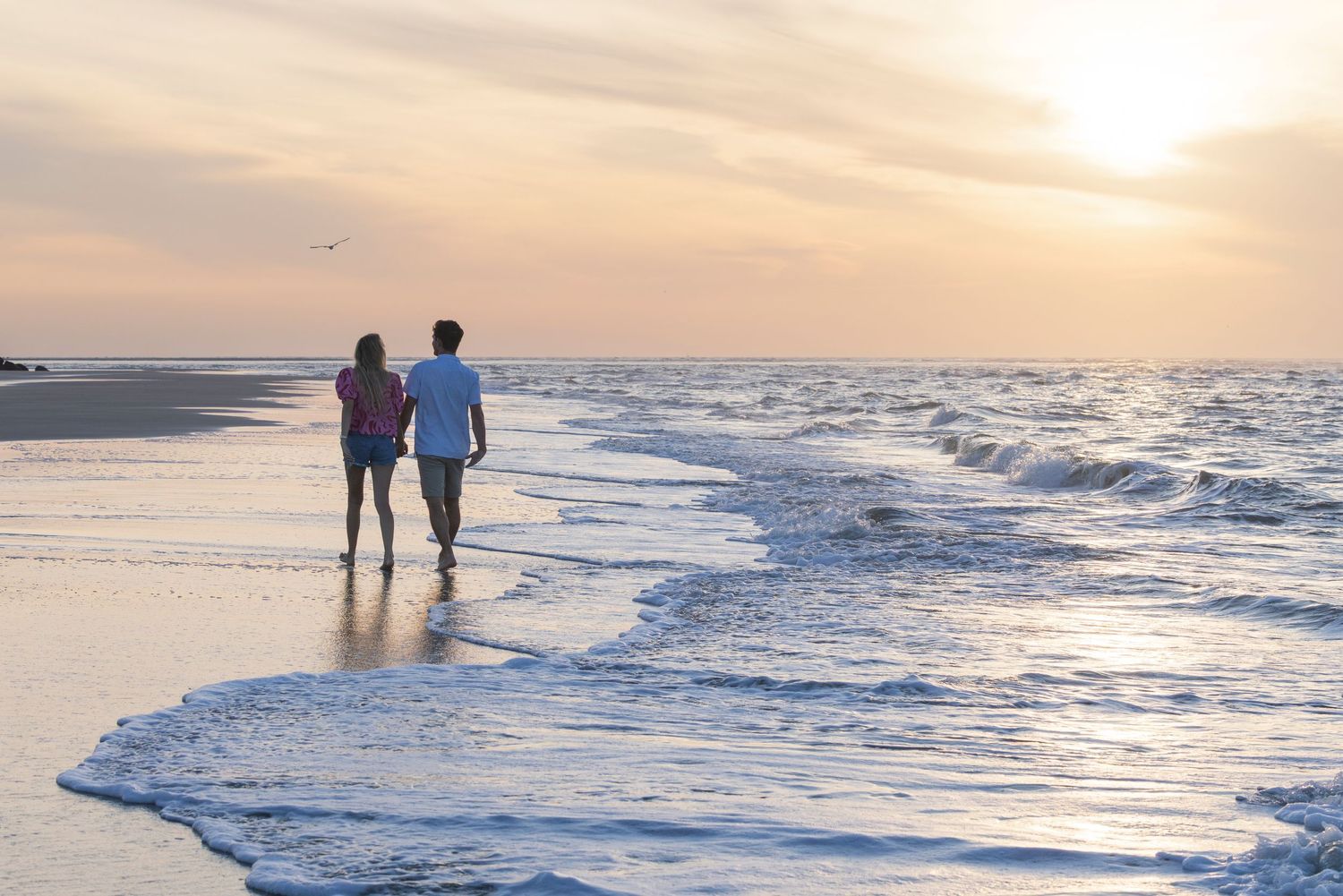 A group sits together on a sandy beach at sunset during a casual outdoor photo session.