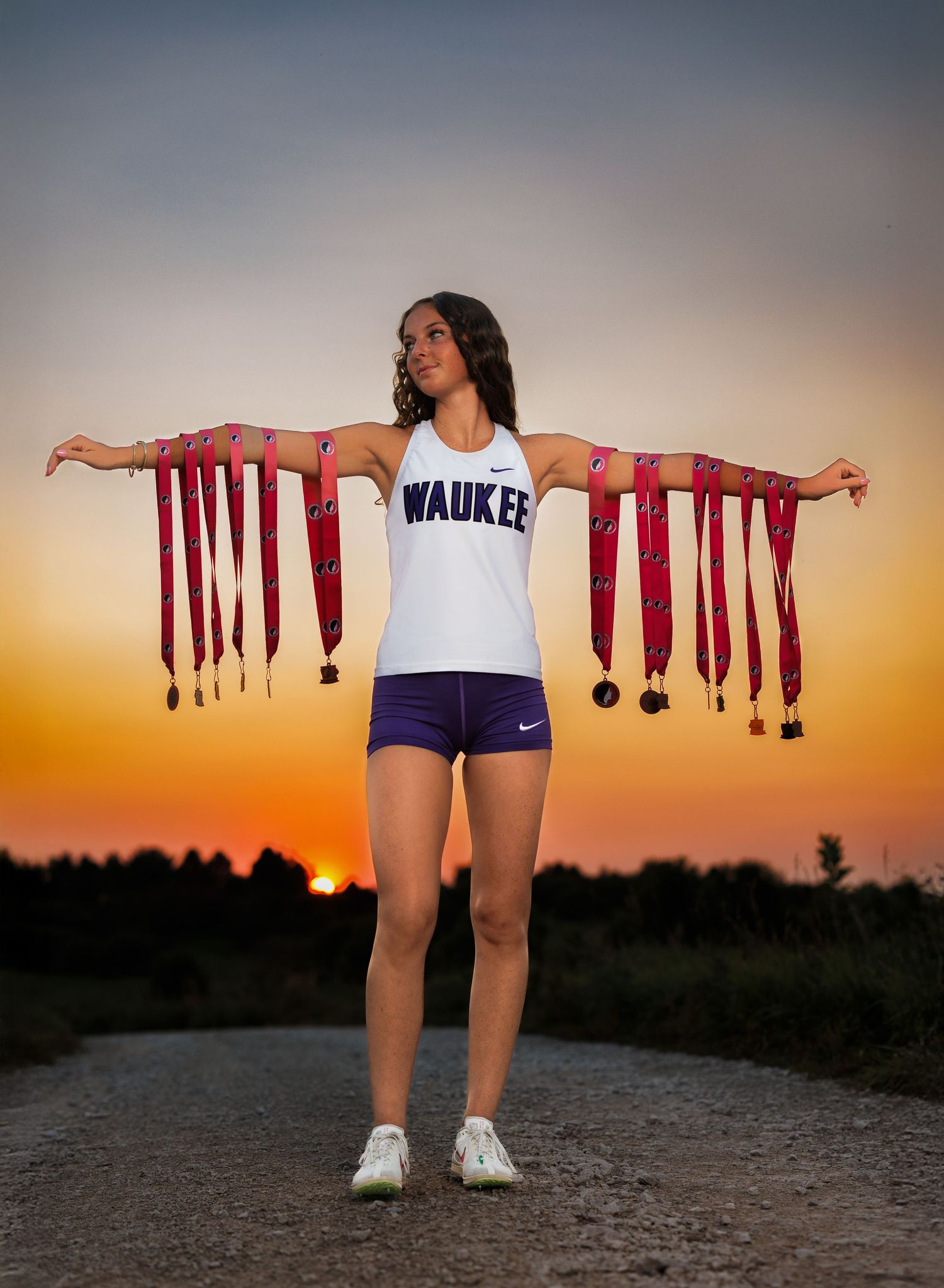 A senior girl track athlete showcasing her state ribbons and medals