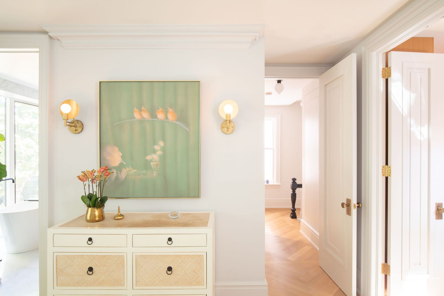 Bright white hallway with wall sconces features cream-colored furniture and soft green accent walls.
