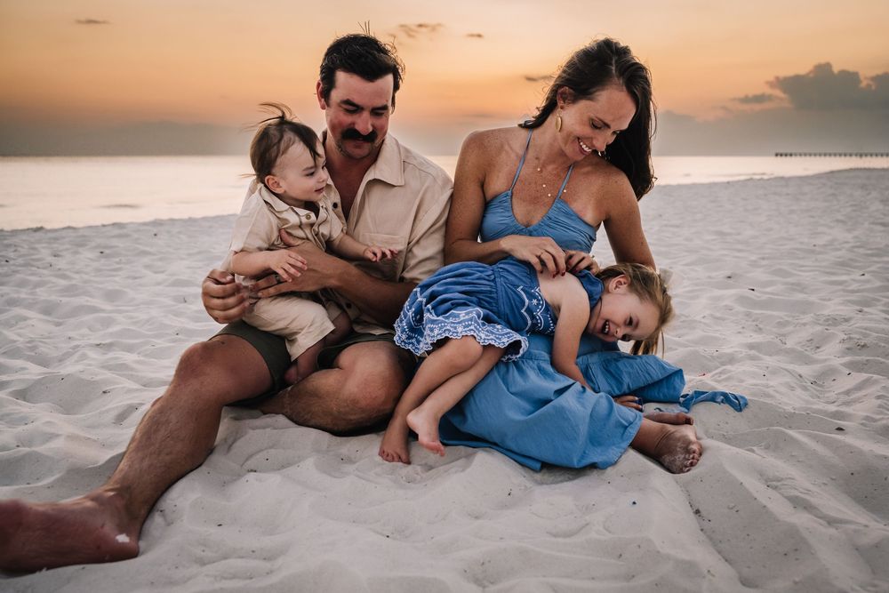 Family enjoying sunset moments together while sitting on a sandy beach.
