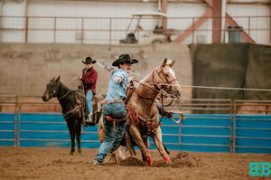 Fast-paced rodeo action inside an indoor arena during a competitive event.