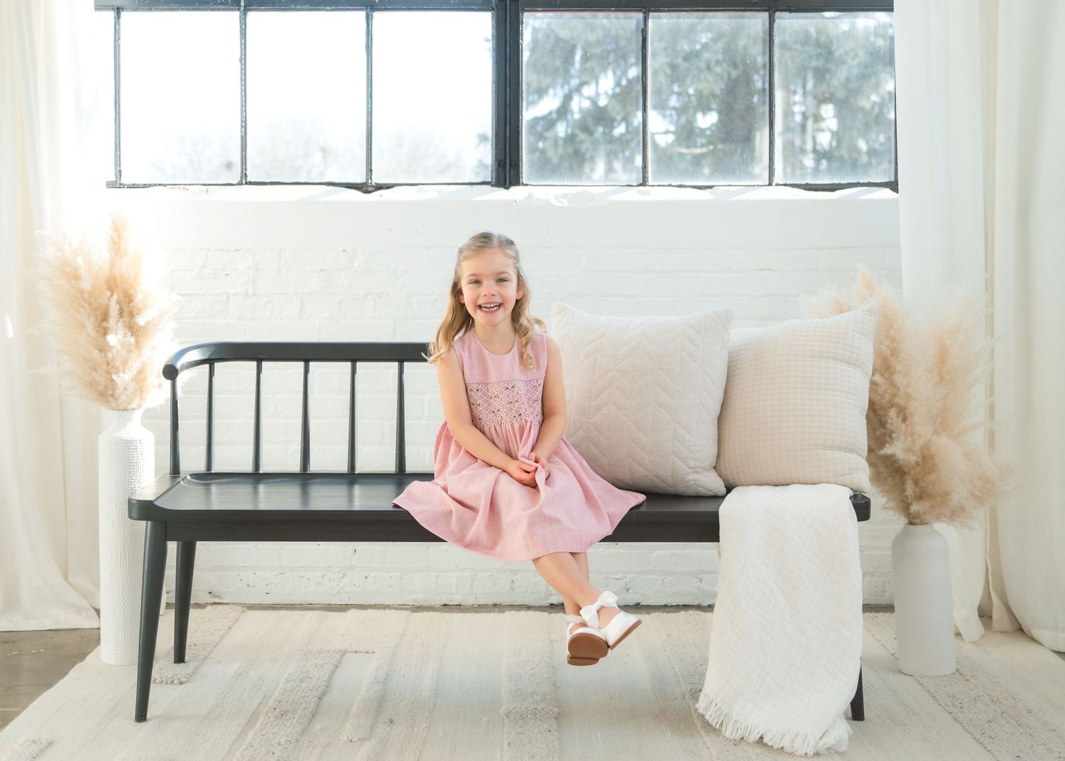First birthday photo setup with large yellow ONE letters, teal chair, and pastel balloons against gray background.