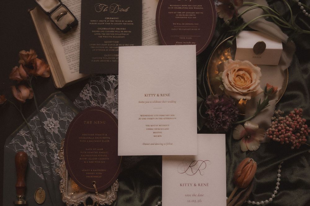 Wedding invitation suite with brown and cream colored stationery displayed among floral elements and coffee beans.