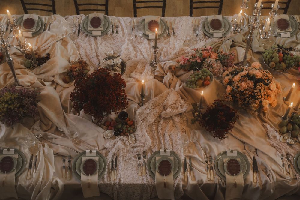 Rustic floral wedding reception decor with dried flowers and greenery hanging from wooden beams in a barn setting.
