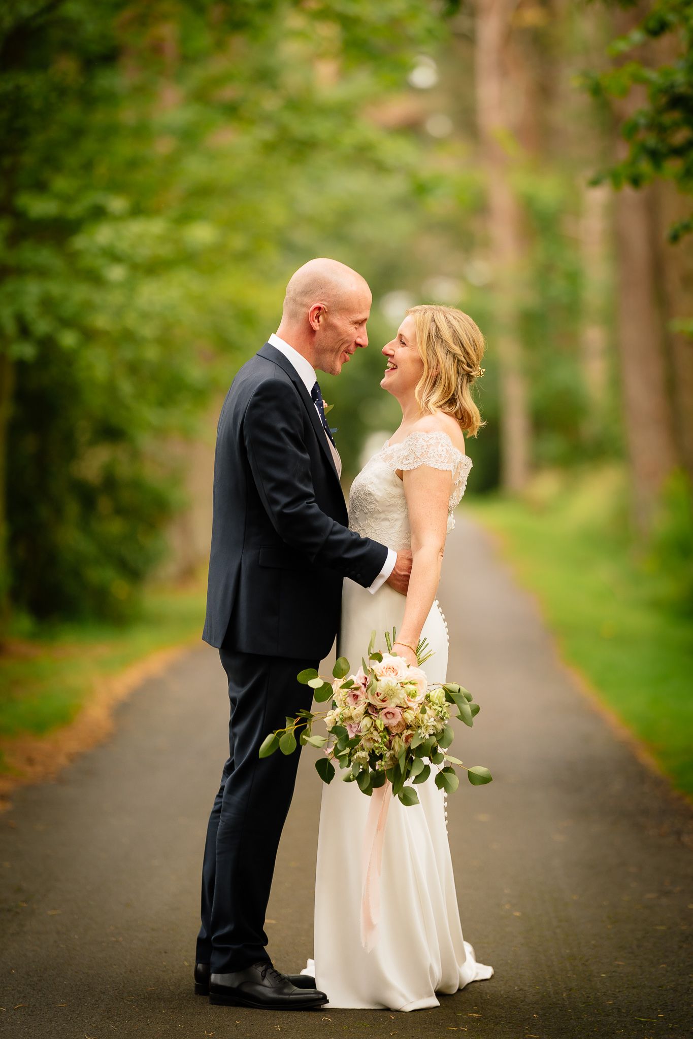 A romantic wedding portrait session on a wooded path with lush greenery. Woodhill Hall.