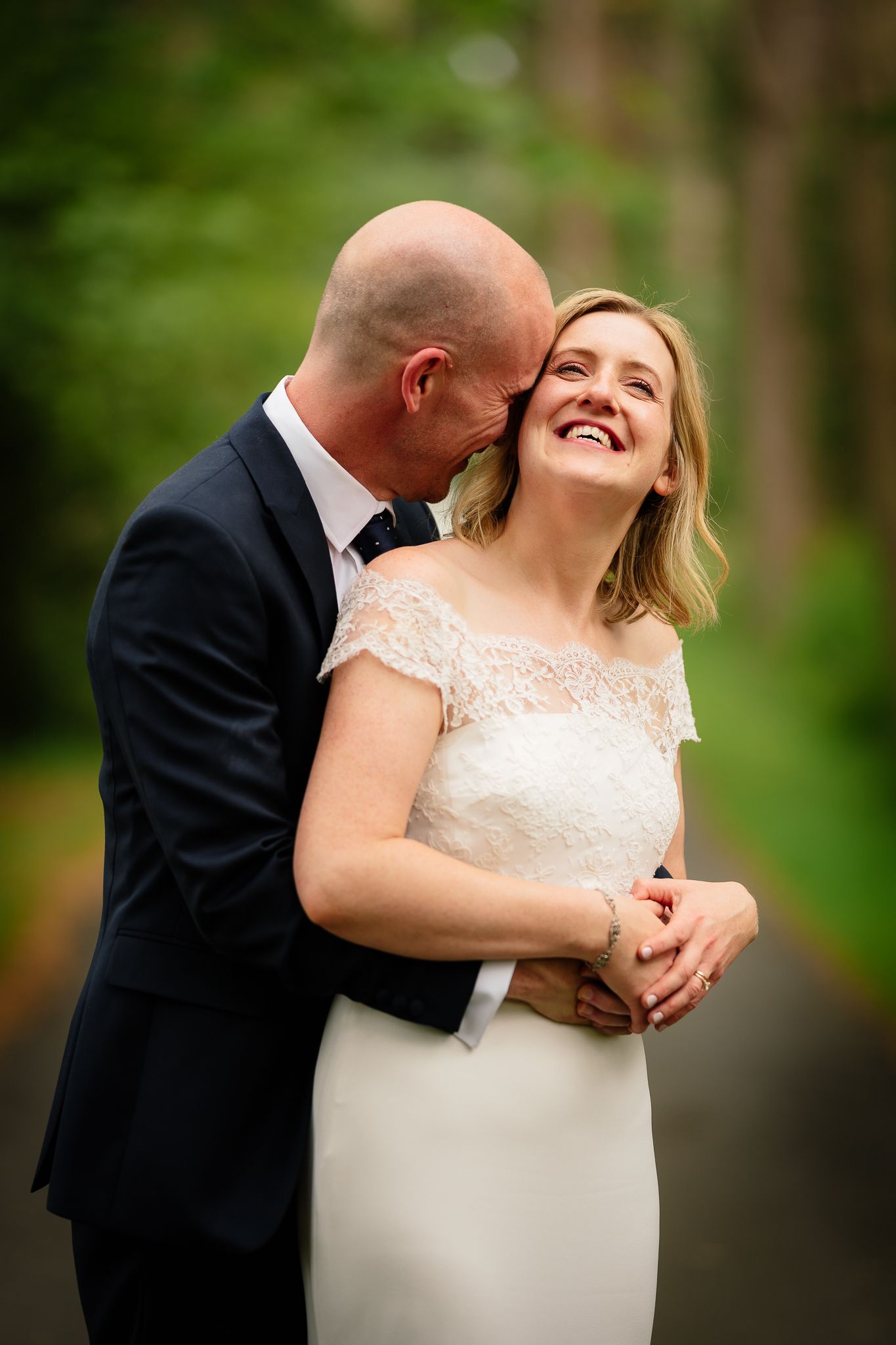Romantic outdoor wedding portrait with couple laughing against a green natural backdrop. Woodhill Hall.