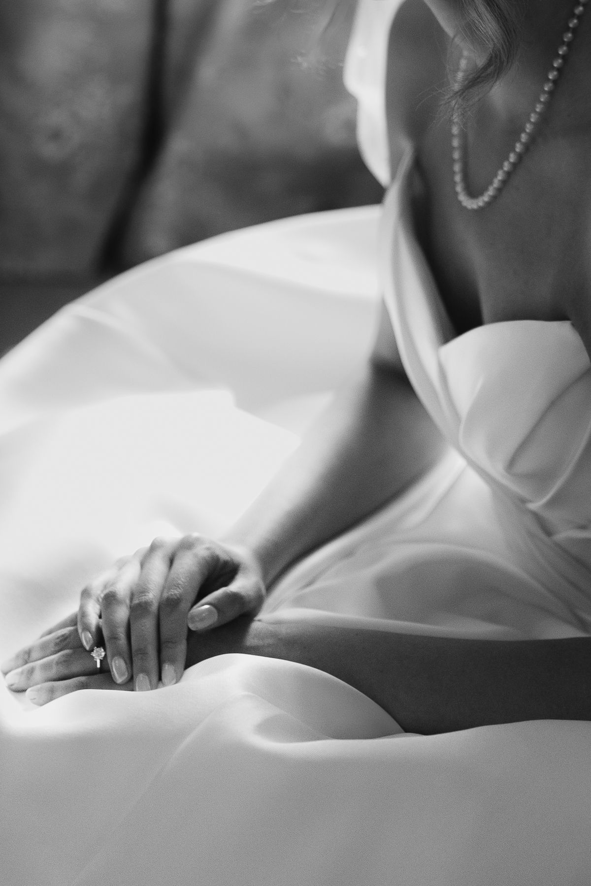 Black and white close-up detail shots of hands gently resting on white fabric with soft lighting.
