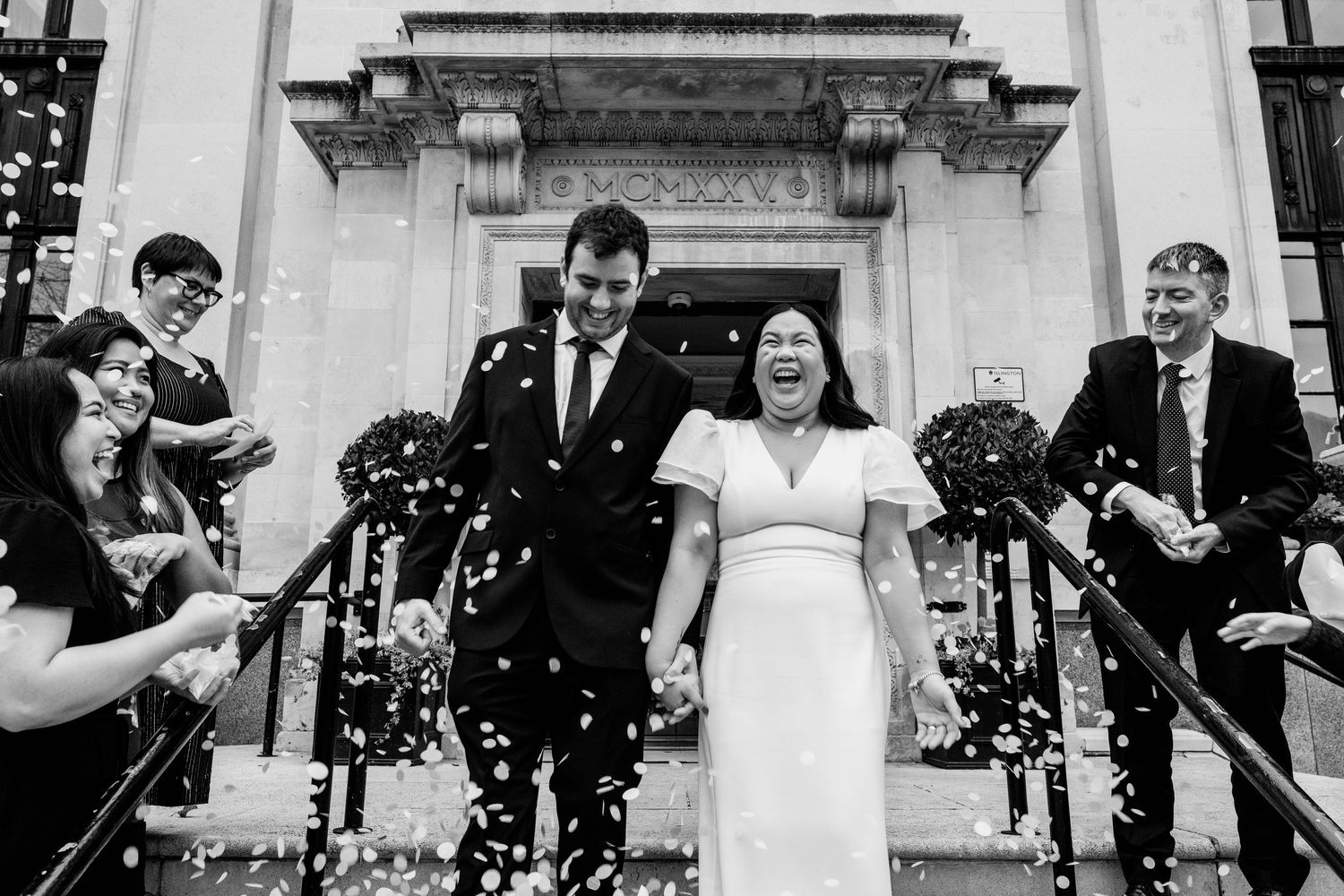 Wedding guests celebrate by throwing confetti at a couple outside Islington Town Hall