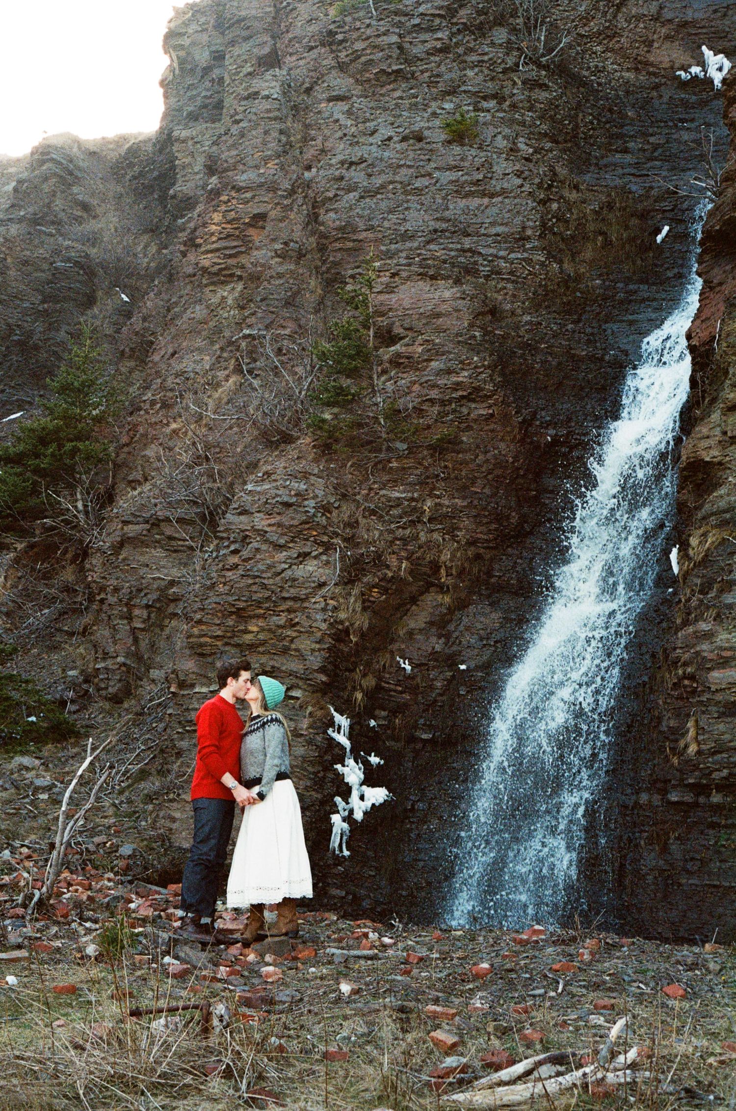 bride and groom kiss at the base of a mountain waterfall