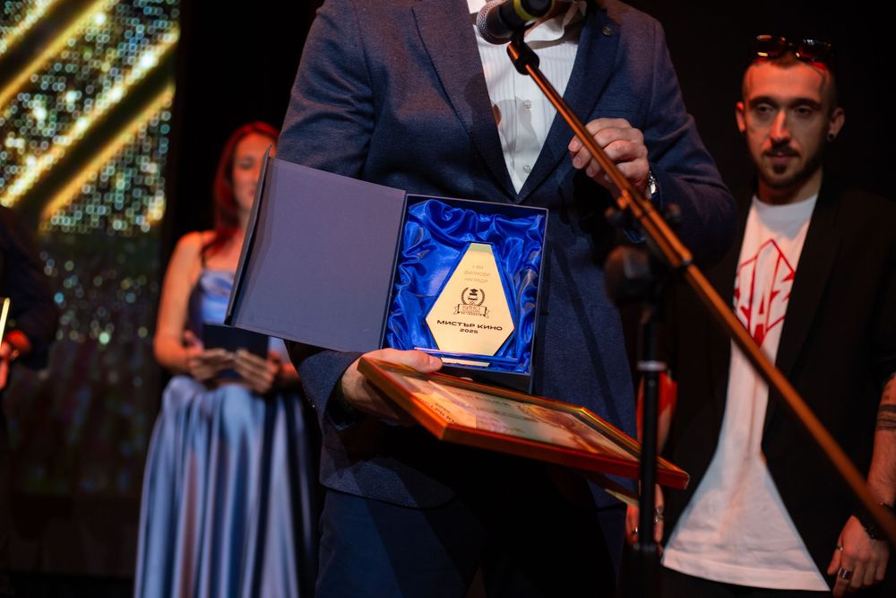 Gold diamond-shaped trophy displayed in blue velvet presentation box at awards ceremony.
