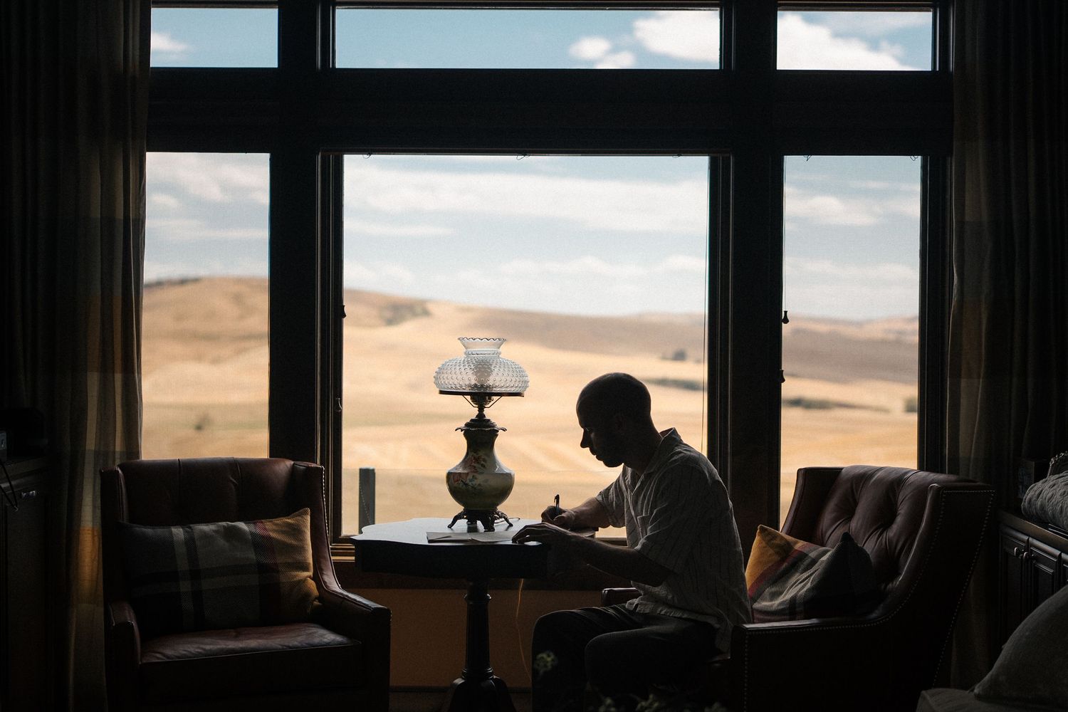 A panoramic view of a desert landscape seen through multiple windows in a dark interior space.