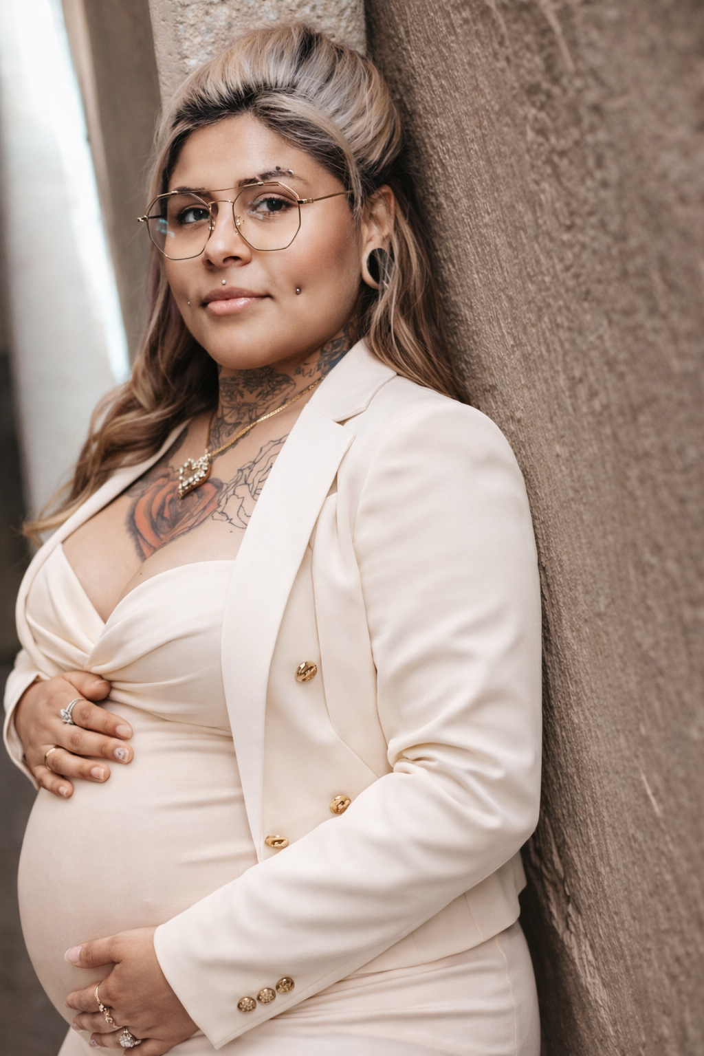 A series of intimate maternity photos showing a woman in a cream blazer against a textured brown wall.