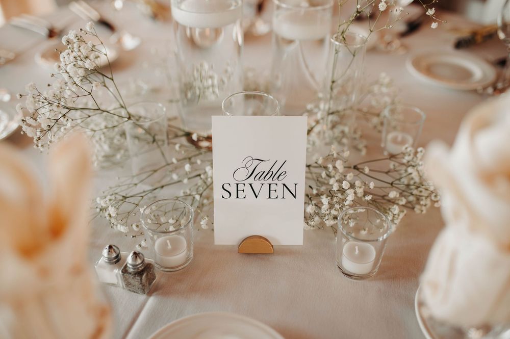 Wedding table number seven card displayed among baby's breath flowers and candles at reception.