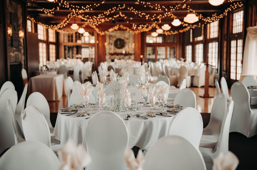 Rustic wedding reception venue with white tablecloths, string lights, and warm wood interior details. Waldenwoods