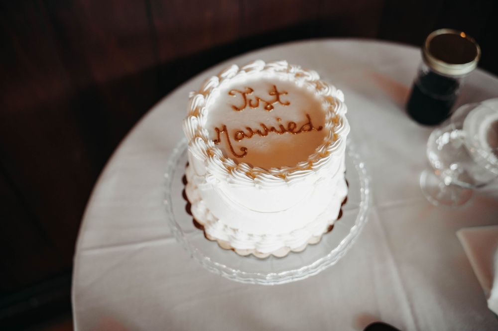 Small round white wedding cake decorated with Just Married written in elegant script frosting.