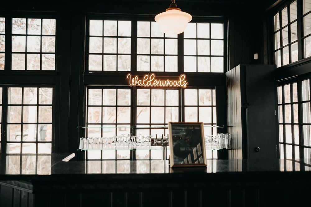 Wallenwoods wedding venue bar area featuring a glowing neon sign and large industrial windows in a dark interior.