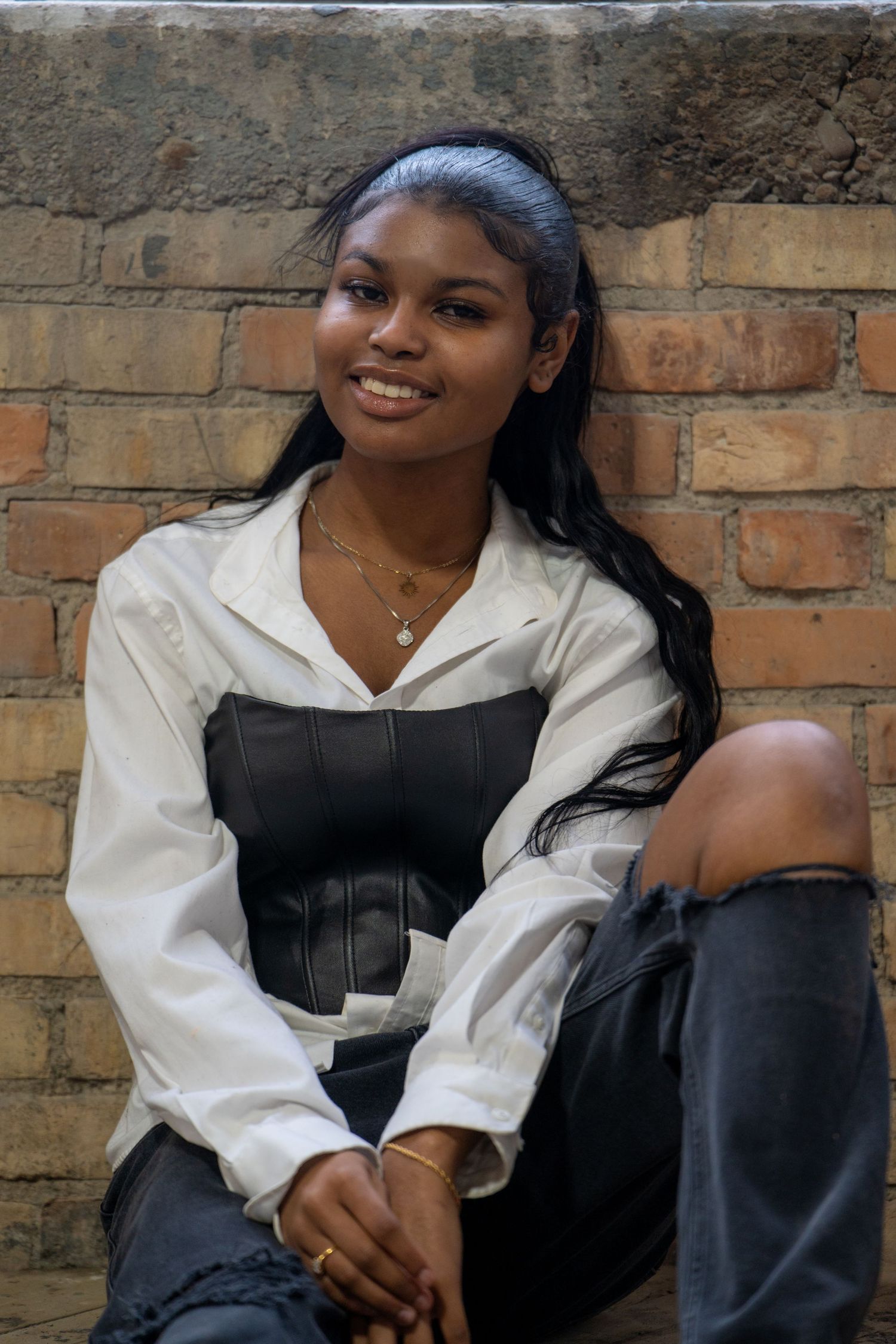 Casual portrait against vintage brick wall in white and black outfit.