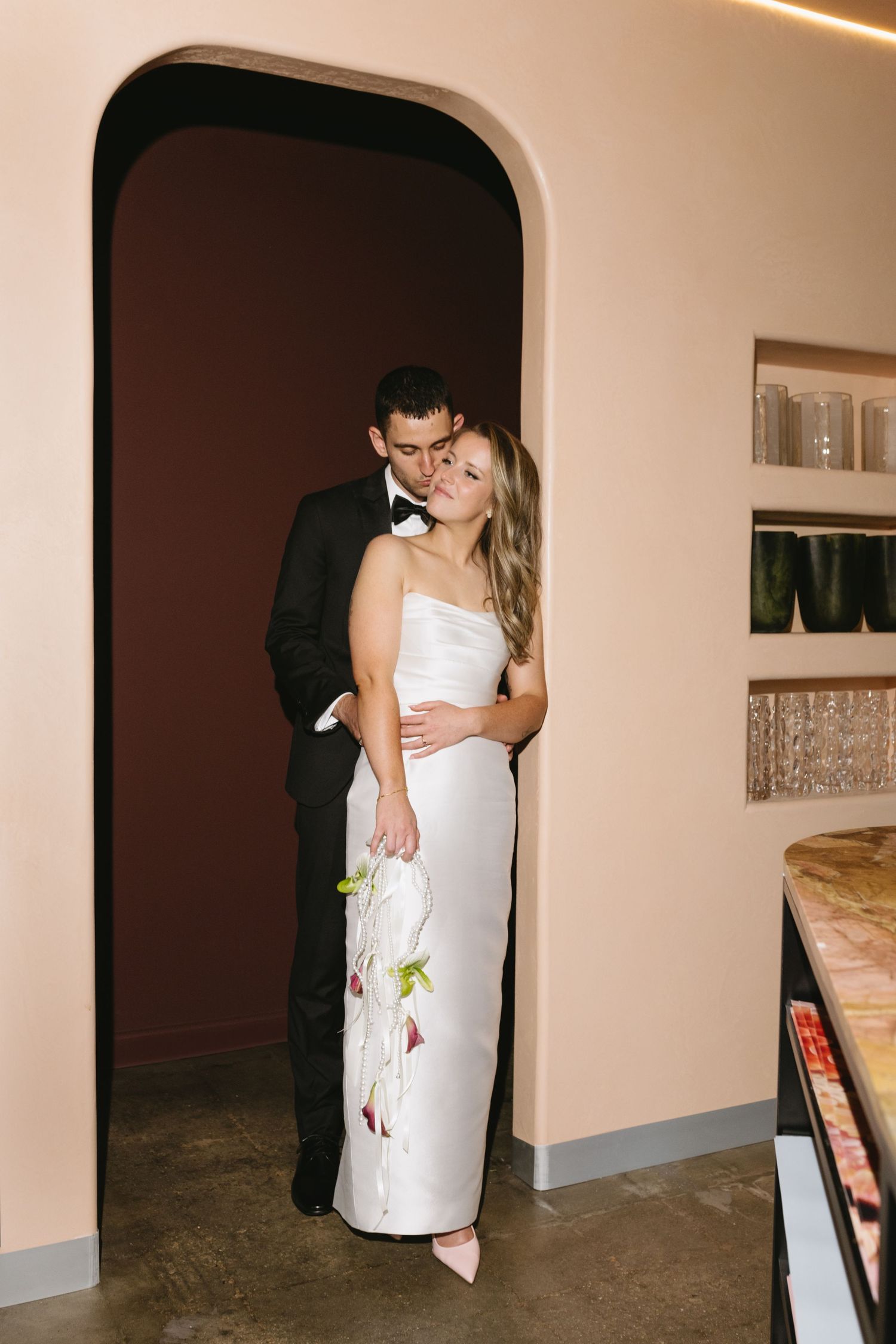 A series of photos showing someone in a white strapless wedding dress posing against a rustic stone and brick wall exterior.