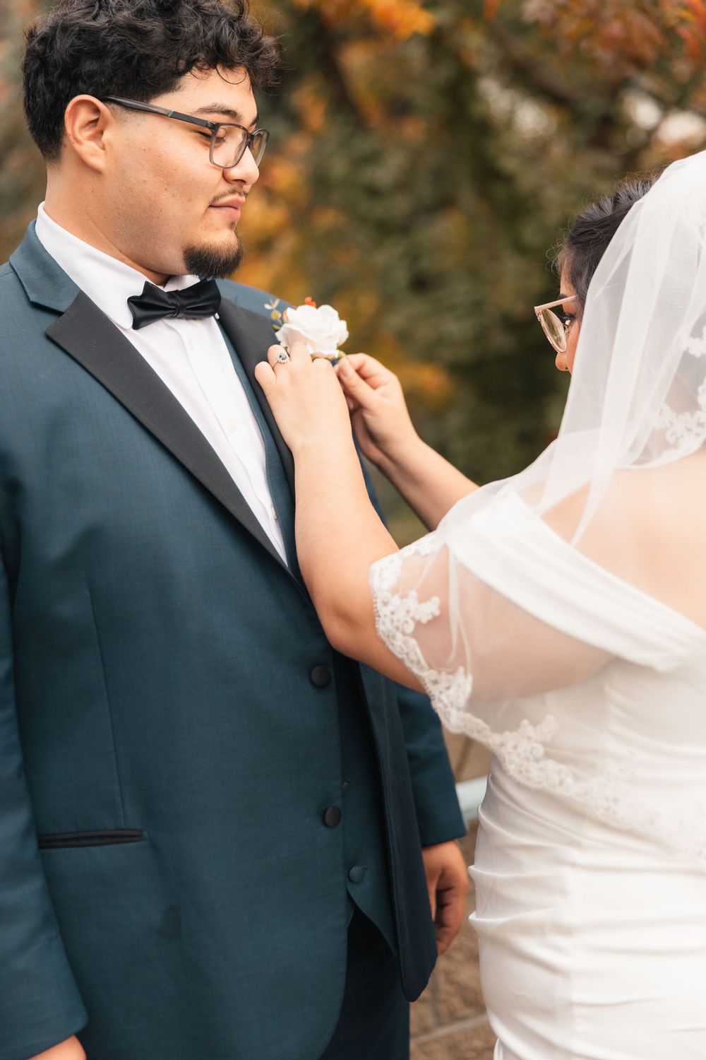 Close-up details of bride and groom's attire during outdoor fall wedding ceremony.