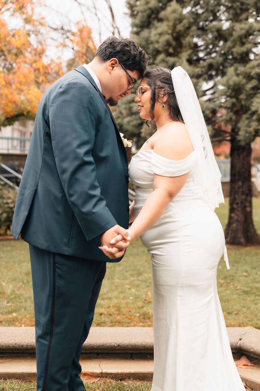 Intimate wedding moment captured in autumn setting with couple holding hands.