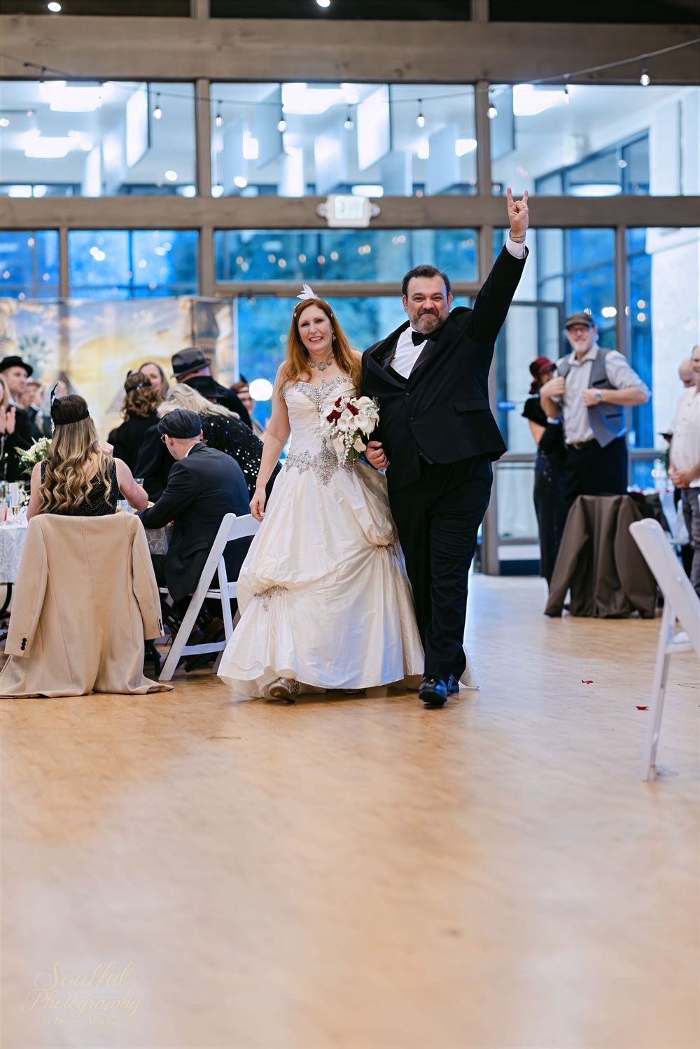 Wedding reception dance floor with couples dancing in an elegant indoor venue with large windows.