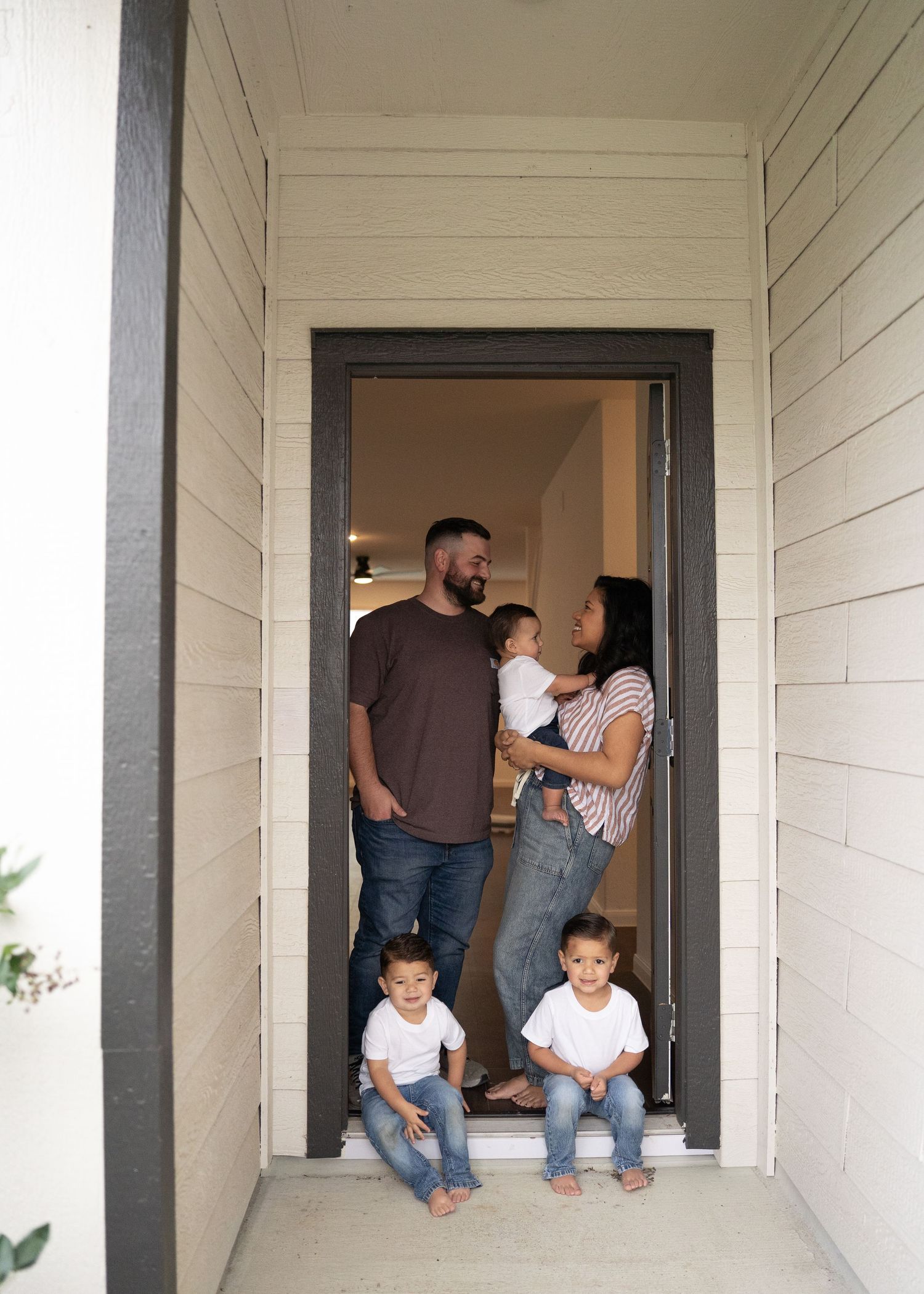 Family portrait in empty home with natural light, showing love and connection as they prepare for a new baby