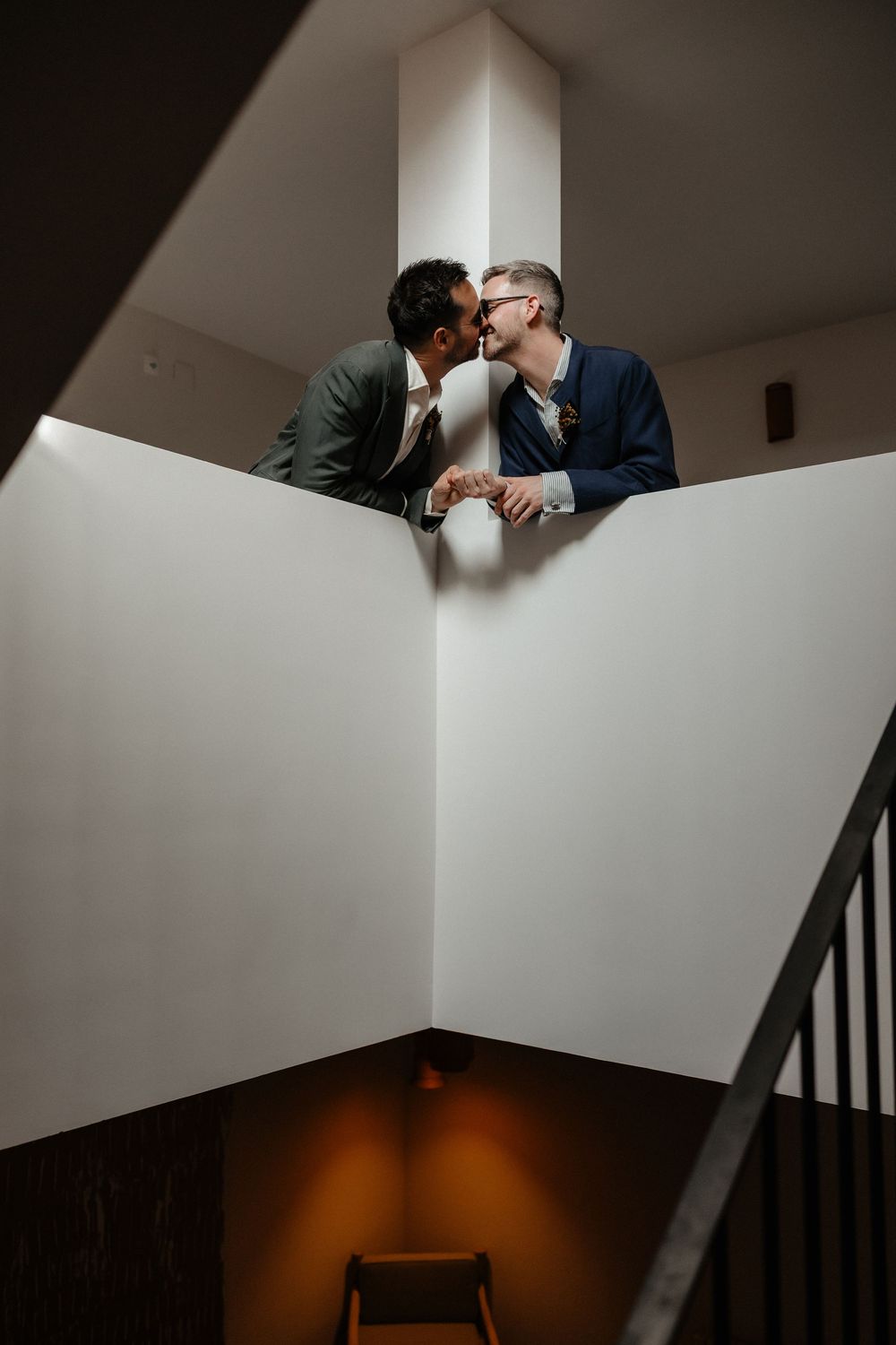 Artistic black and white series of a couple sharing intimate moments on a staircase with dramatic lighting and shadows.