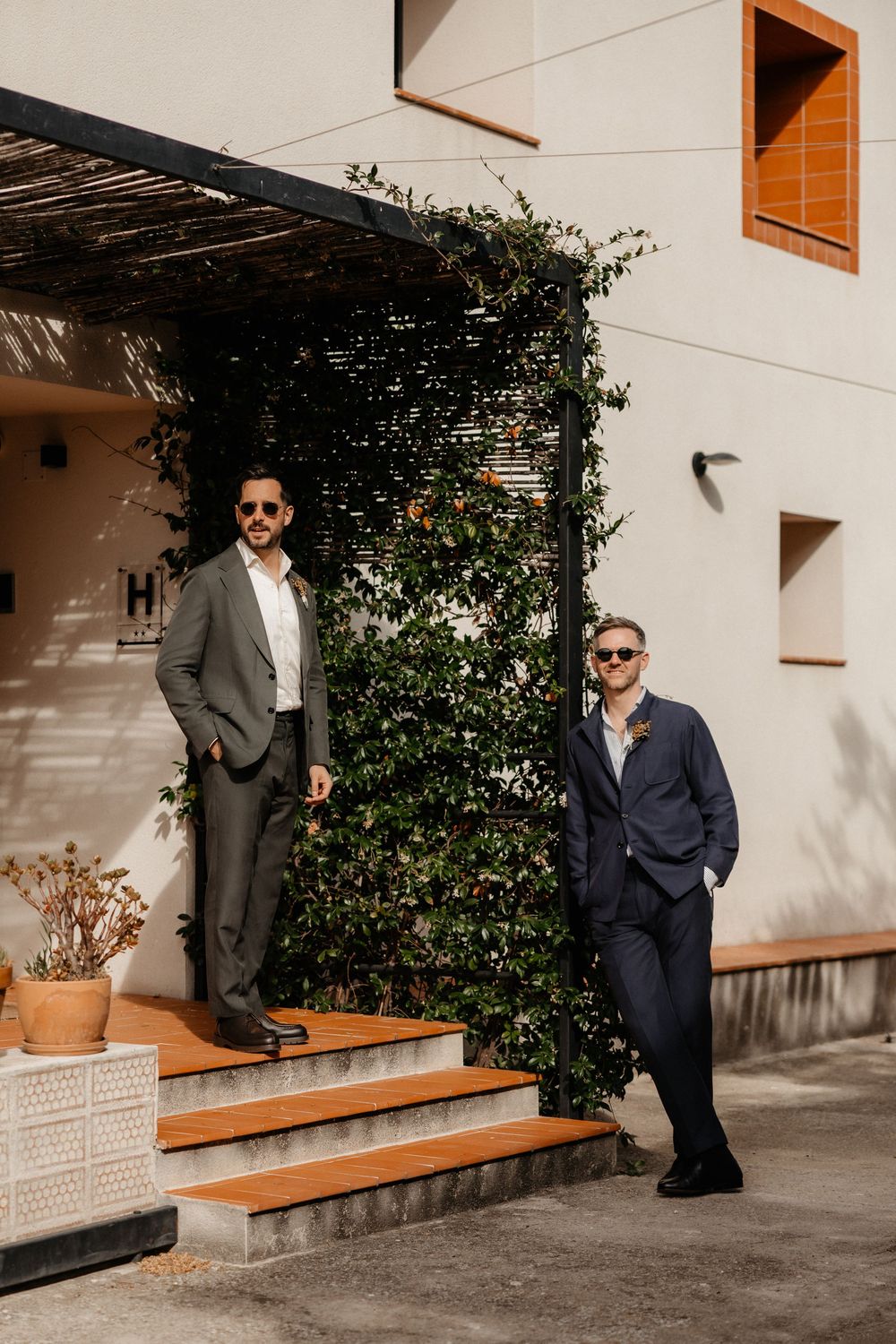 A sequence of photos showing people in dark suits posing against a white wall with wooden benches and greenery.