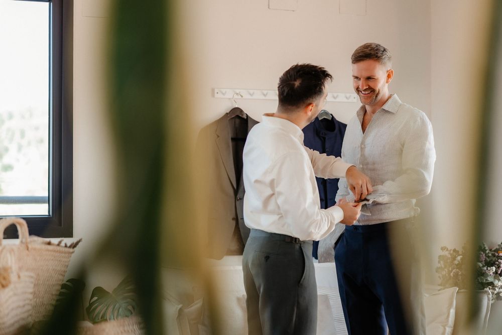 Two people in white button-down shirts share an intimate dance moment in a sunlit room.