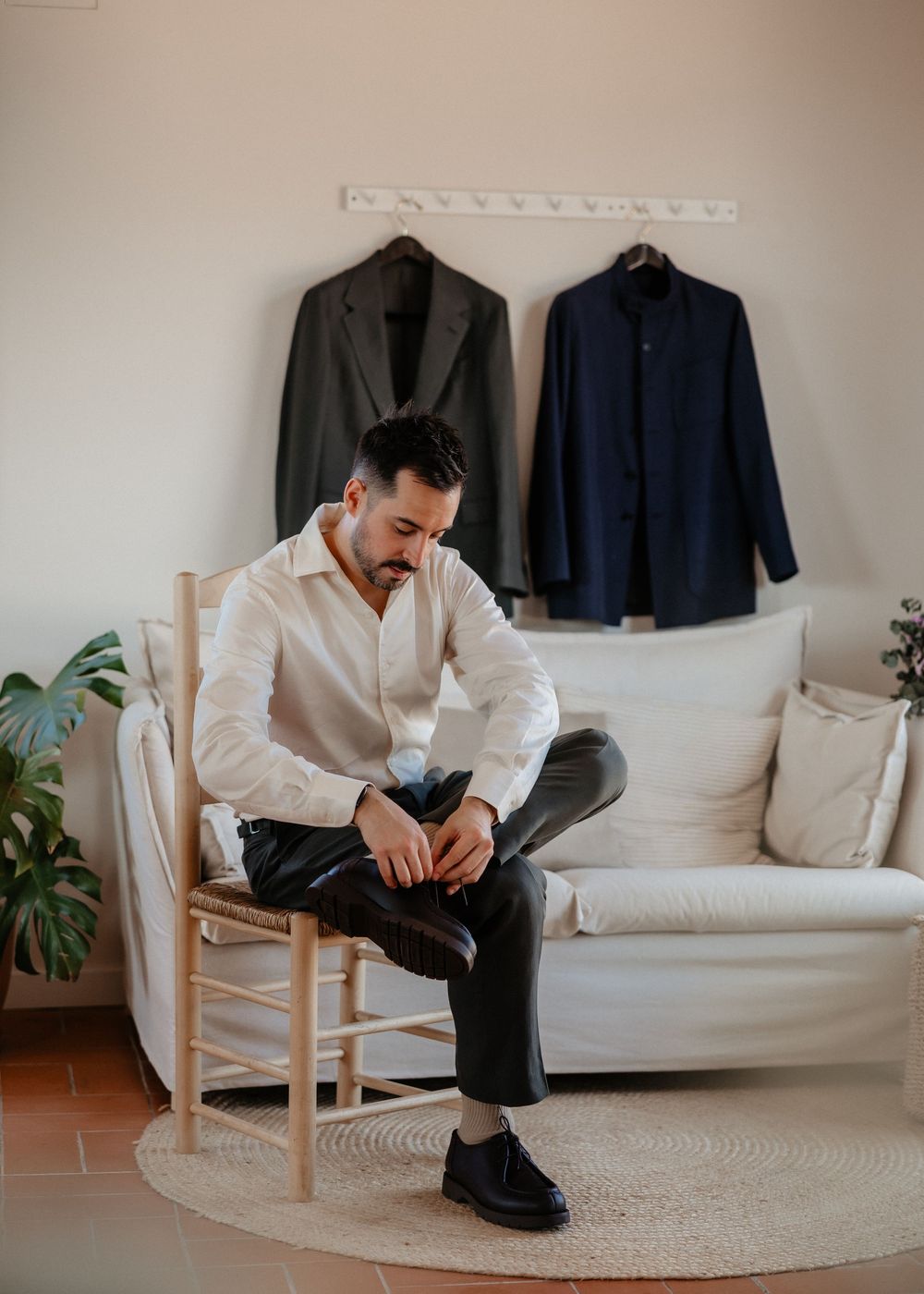 A series of images showing someone sitting in a white chair against a neutral wall with jackets displayed in the background.