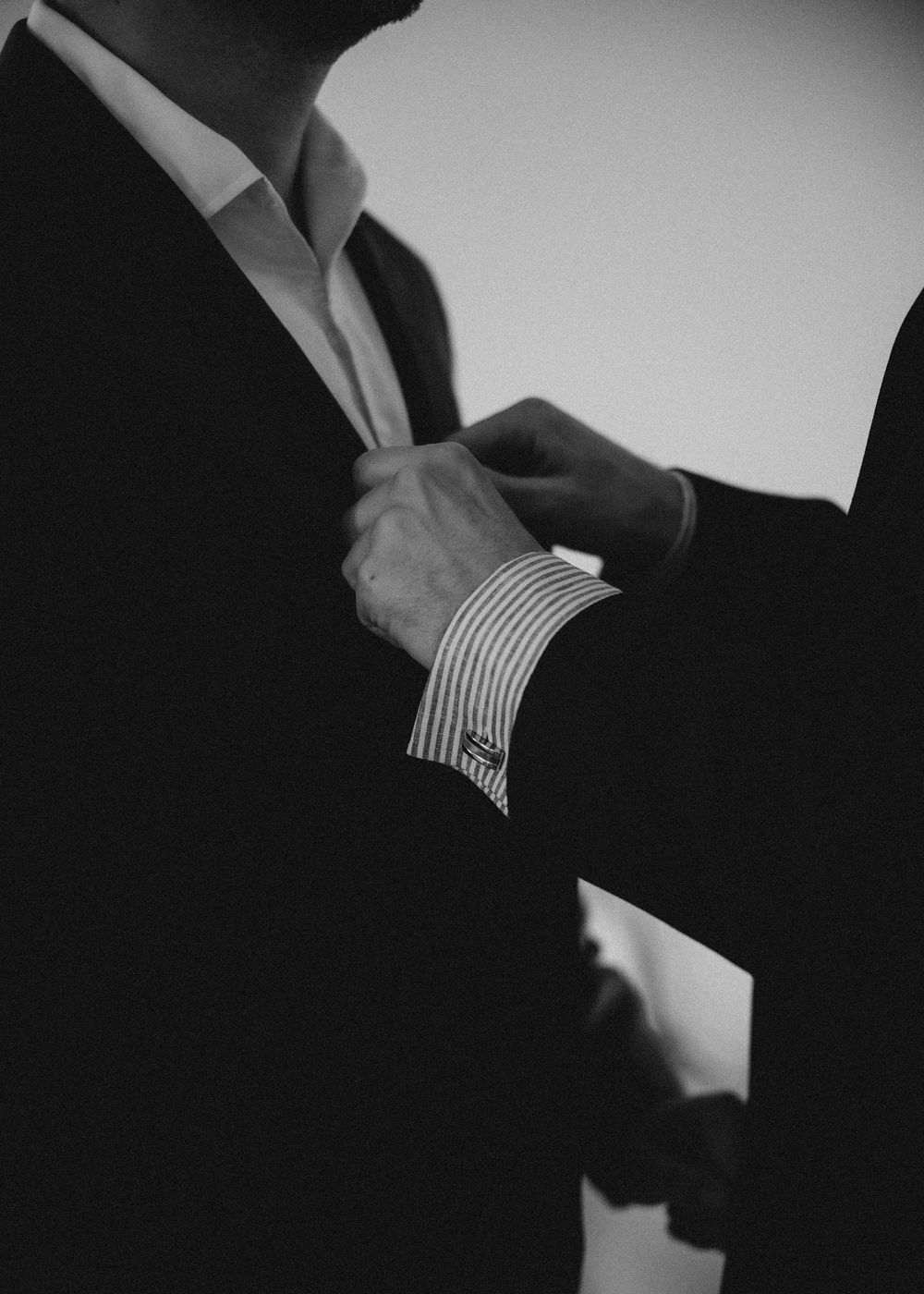 Close-up black and white images showing hands adjusting dress shirt cuffs and formal attire details.