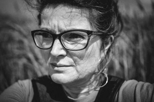 A dramatic black and white portrait showing intense expression through glasses.