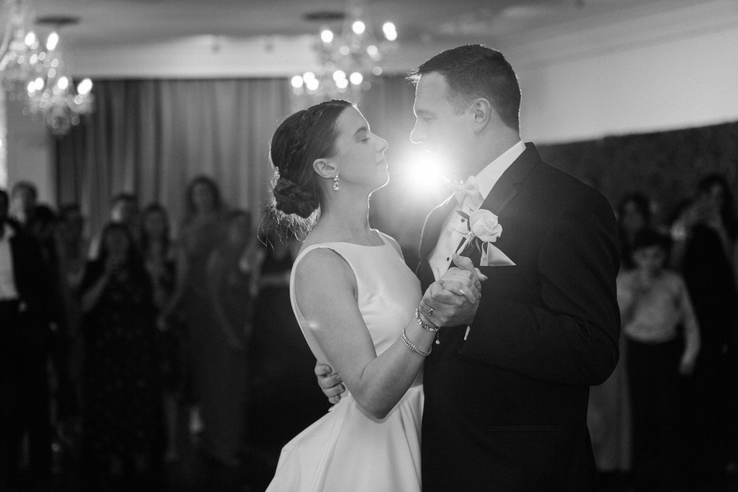 Newlyweds share their first dance at an elegant wedding reception with guests watching in the background.