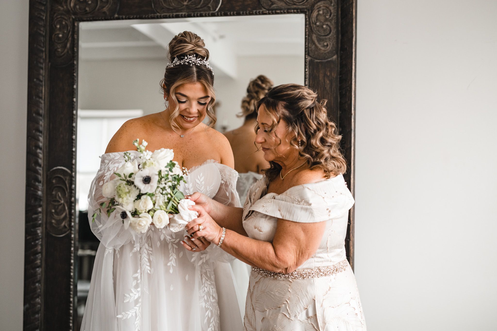 Bridesmaids in black dresses share joyful moments with the bride holding white floral bouquets.