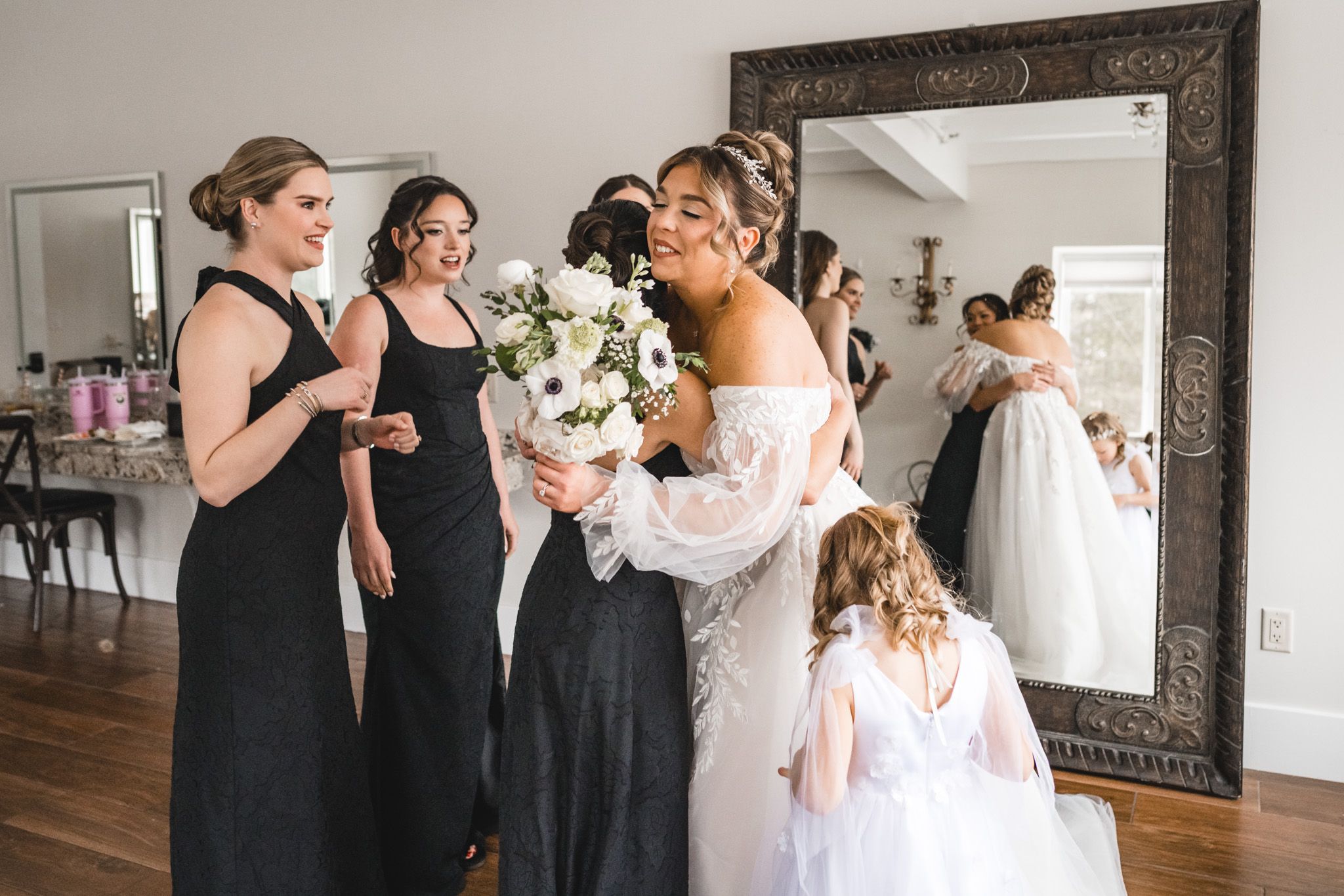 Wedding party gathers in an ornately framed mirror reflection during pre-ceremony preparations.