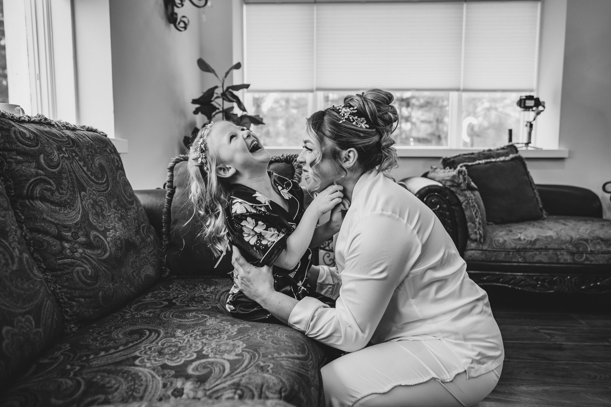 Black and white photo of wedding preparation moment in living room setting.