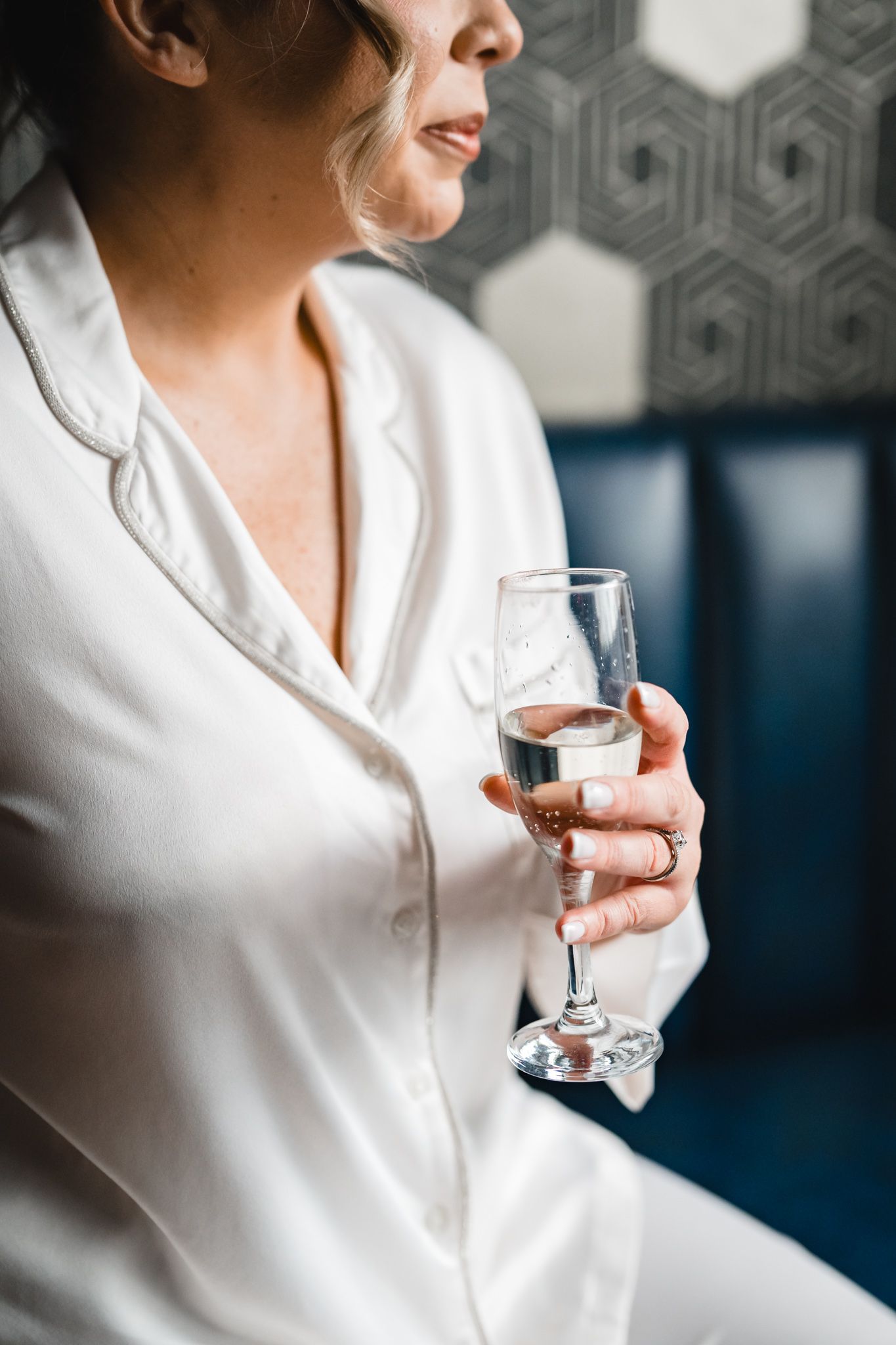 Close-up of champagne glass held by person wearing white silk robe.