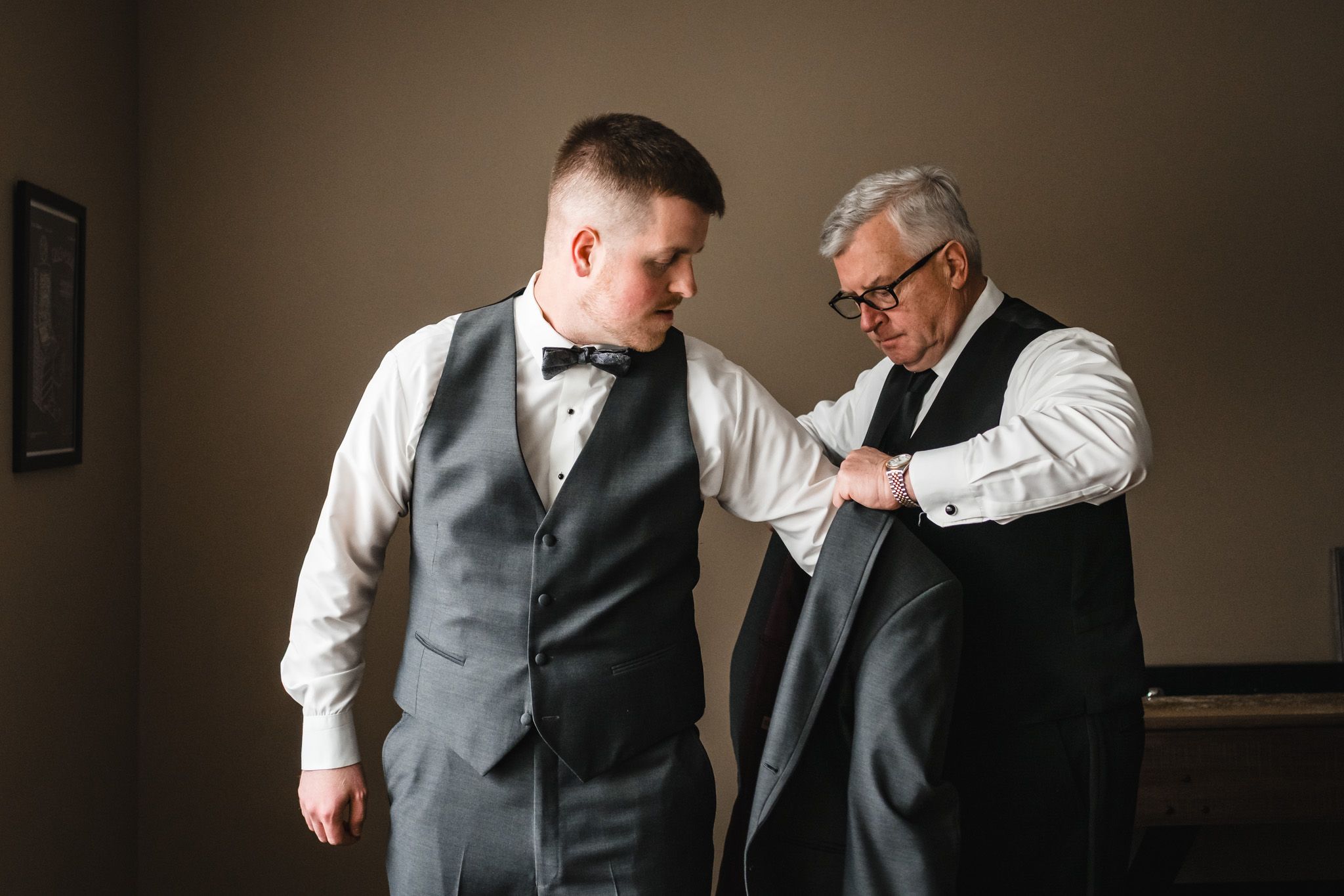 A touching moment between two men in formal wear as they prepare for a special occasion.