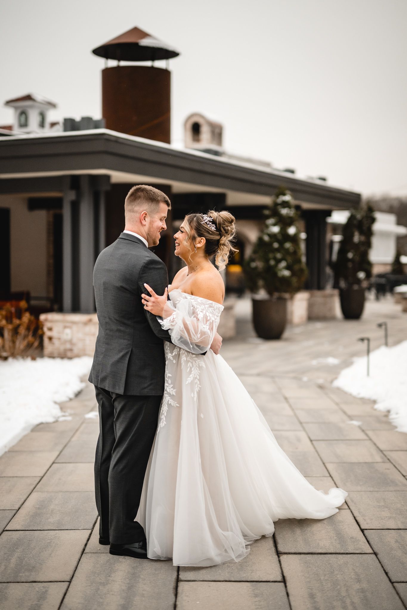 A romantic moment captured on a stone patio with modern architecture and winter scenery.