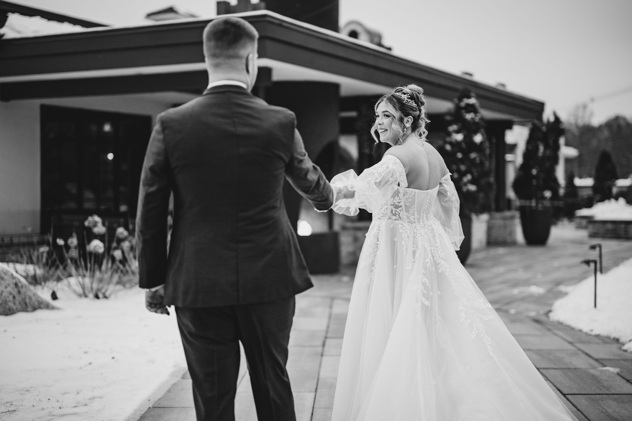 A black and white wedding photo showing a couple sharing a moment on an outdoor walkway.