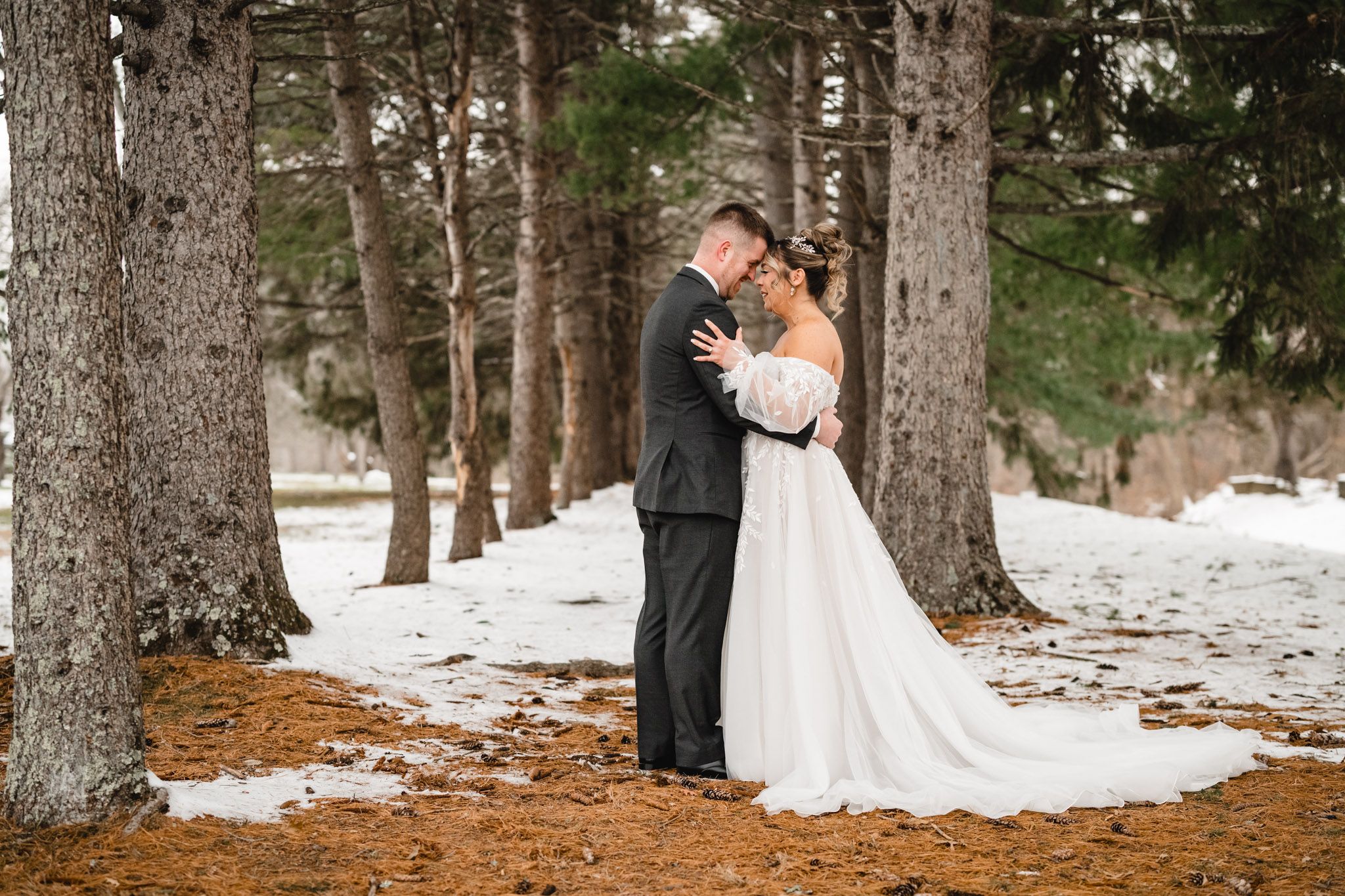 Newlyweds embrace during winter wedding photoshoot in forest.