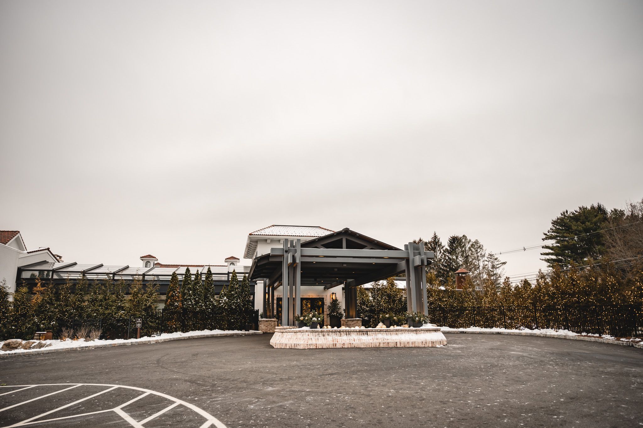 An exterior view of a modern wedding venue with a covered entrance on an overcast day.