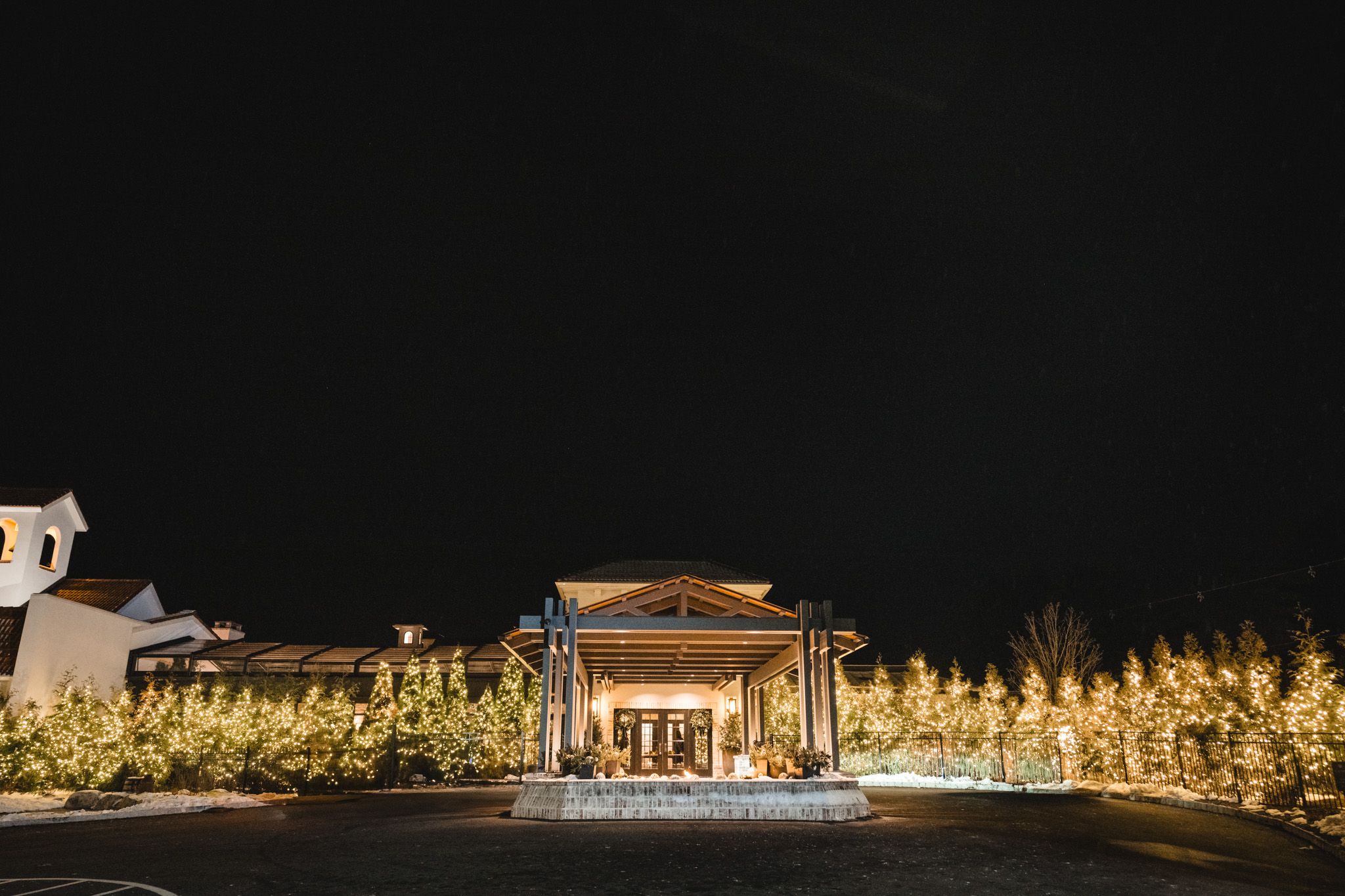 Nighttime exterior view of an illuminated wedding venue with architectural lighting.