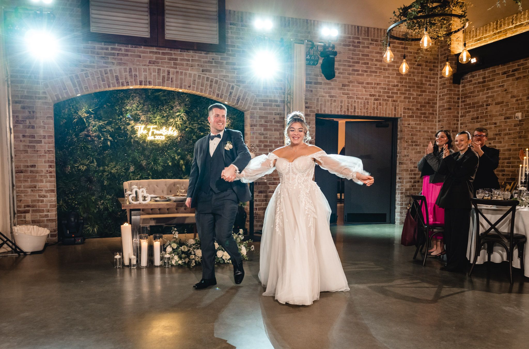 Wedding celebration in a spacious brick venue with string lights and dancing guests.