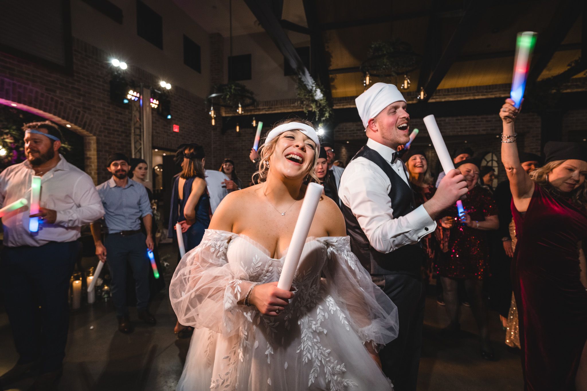 Wedding celebration on the dance floor with light-up foam sticks and festive atmosphere.
