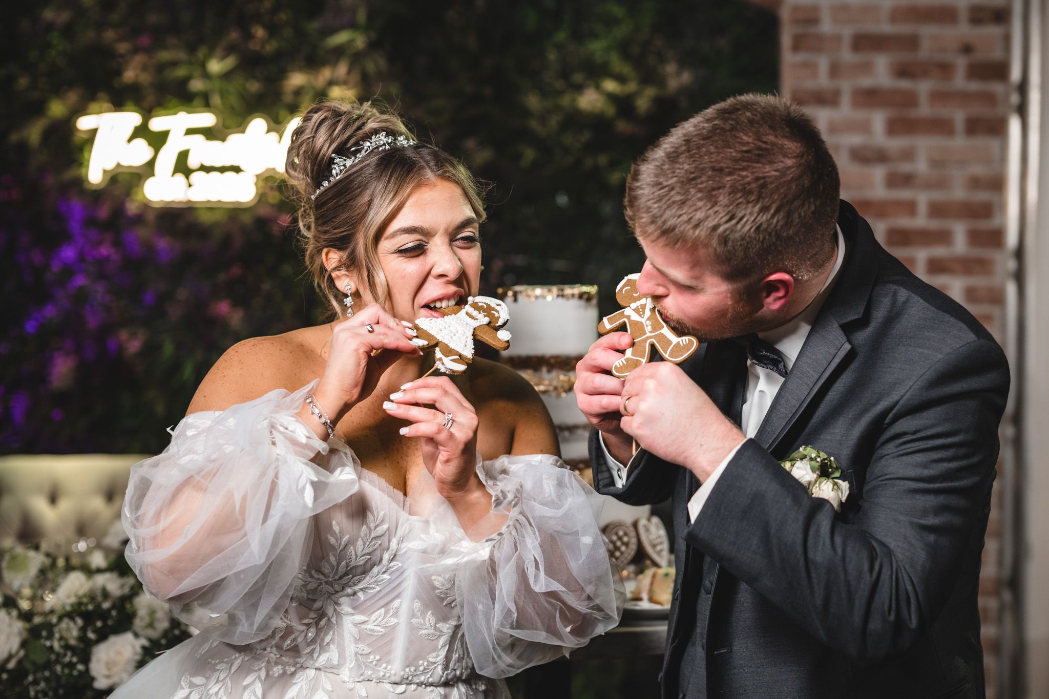 Newlyweds share a sweet moment drinking from teacups in an outdoor garden setting.