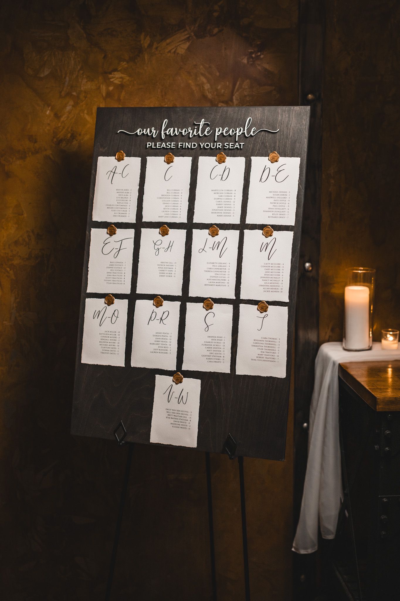 Wedding seating chart display with paper cards arranged on a dark background with candlelight.